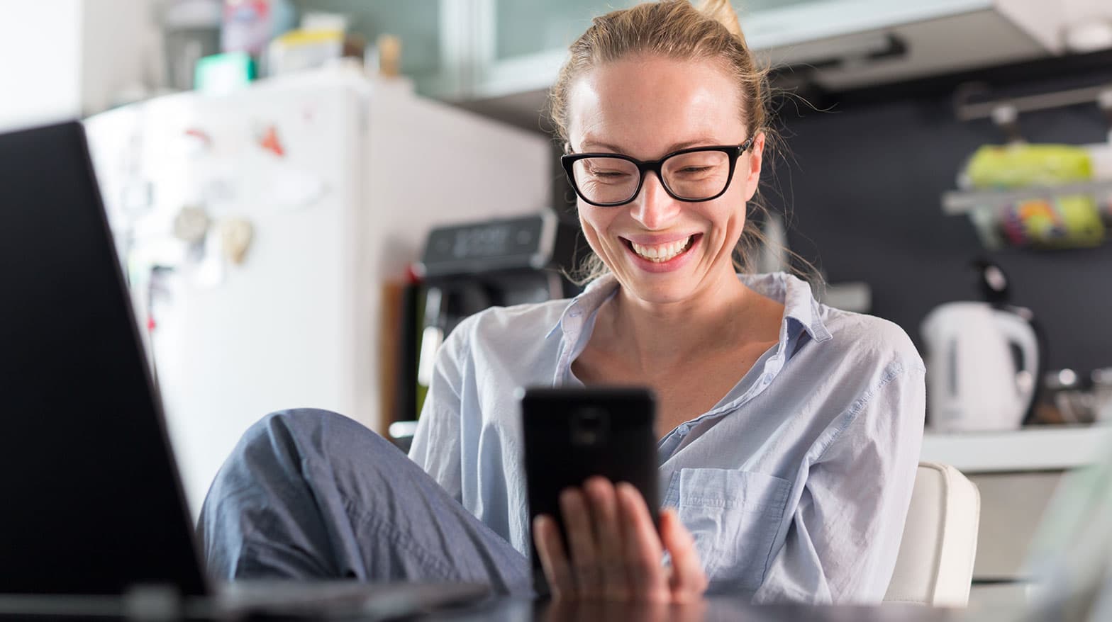 A woman smiling at her mobile phone