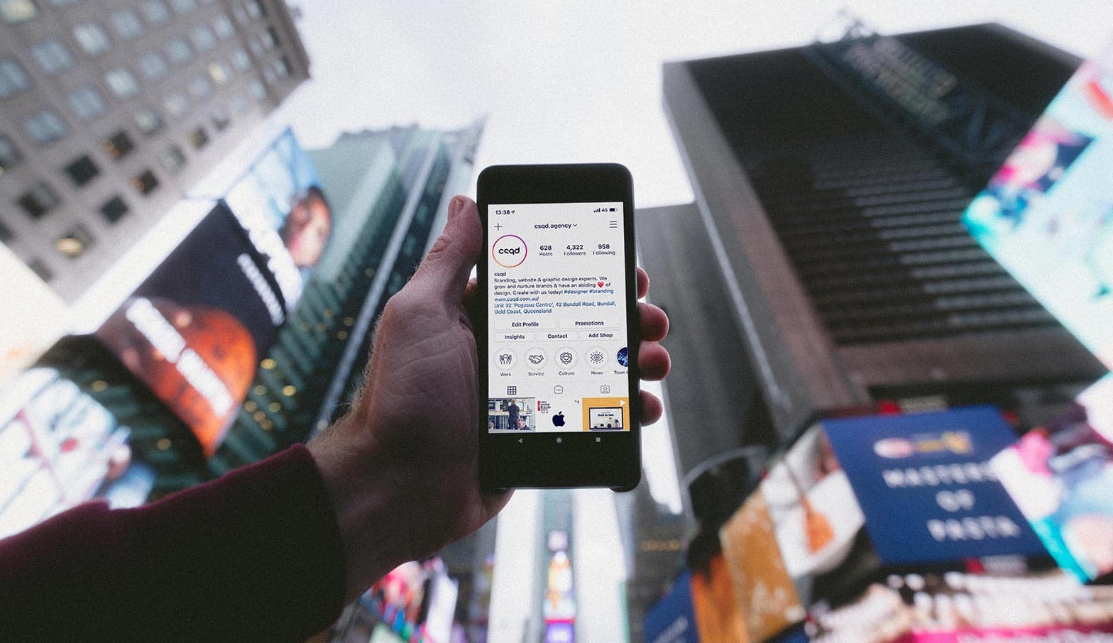 A mobile phone being held up in front of the camera with social media content on screen