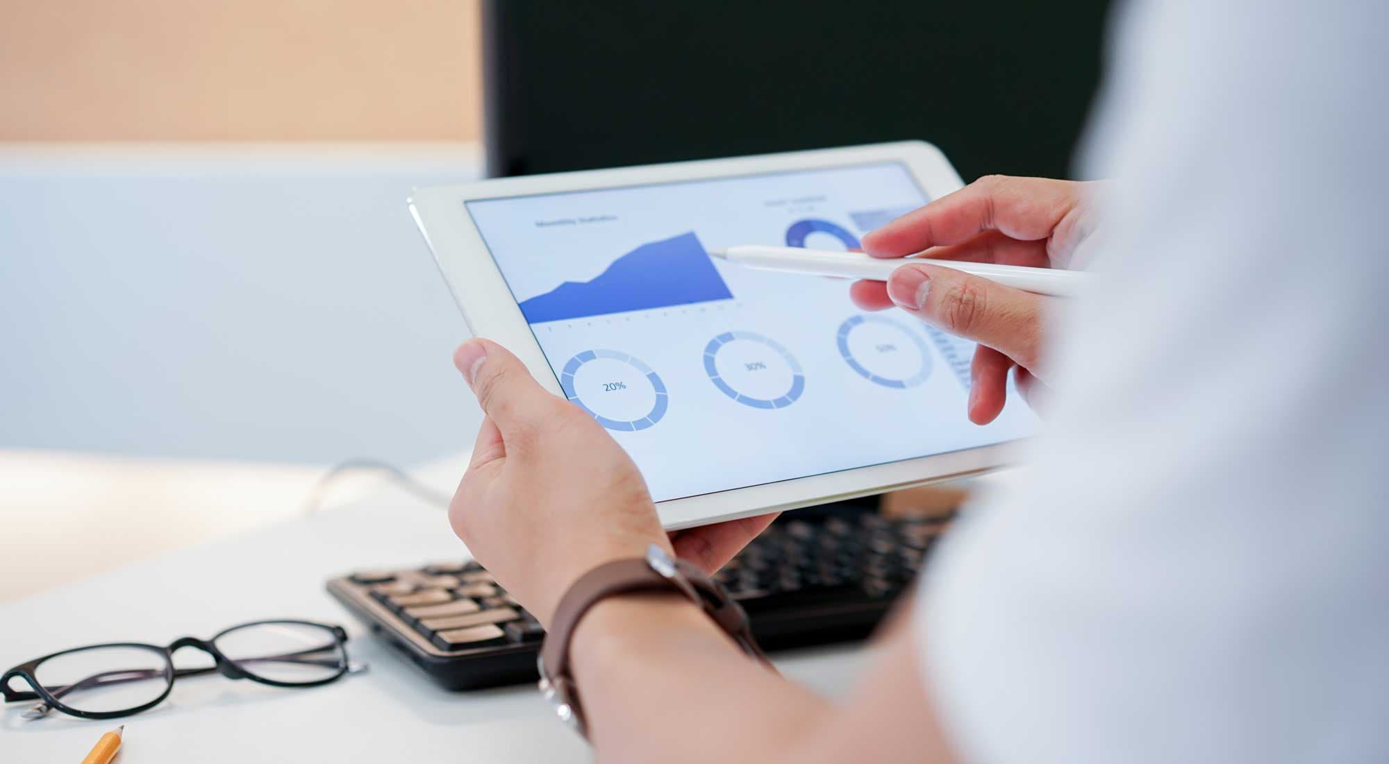 A person looking at an iPad with a chart showing a marketing budget