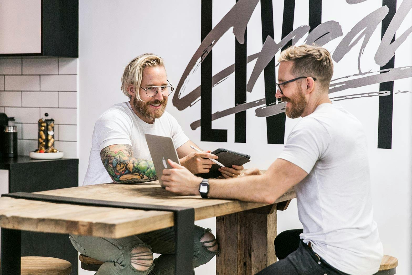 Two men discussing strategy at a table with iPads